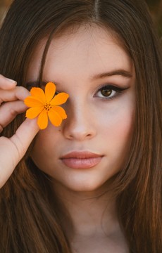woman-holding-orange-flower-over-right-eye-2009827.jpg