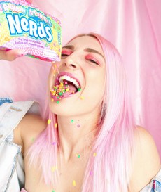 woman-with-pink-hair-pouring-nerds-candy-in-her-mouth-2156656.jpg