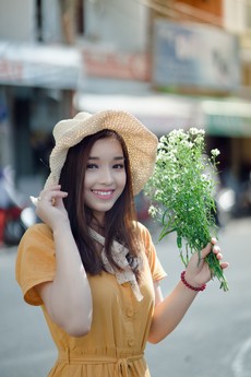 smiling-woman-wearing-hat-holding-white-petaled-flower-1408977.jpg