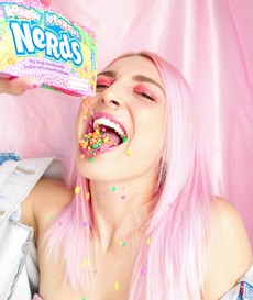 woman-with-pink-hair-pouring-nerds-candy-in-her-mouth-2156656.jpg